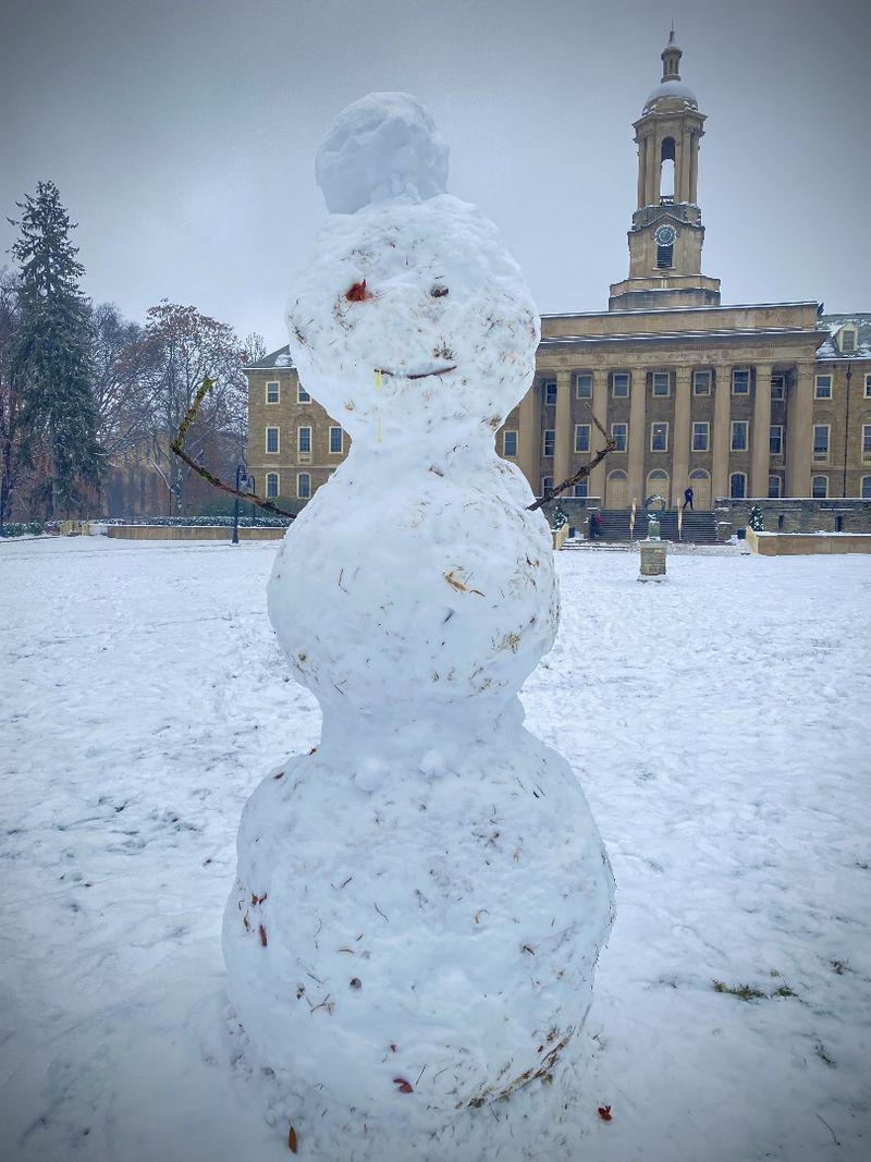 A snowman with Old Main in the background